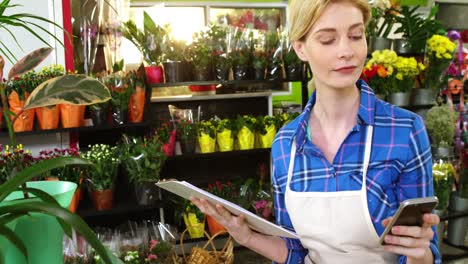 florista usando un teléfono móvil en una floristería
