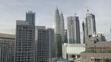 forward aerial shot of kuala lumpur skyline and girl by rooftop pool