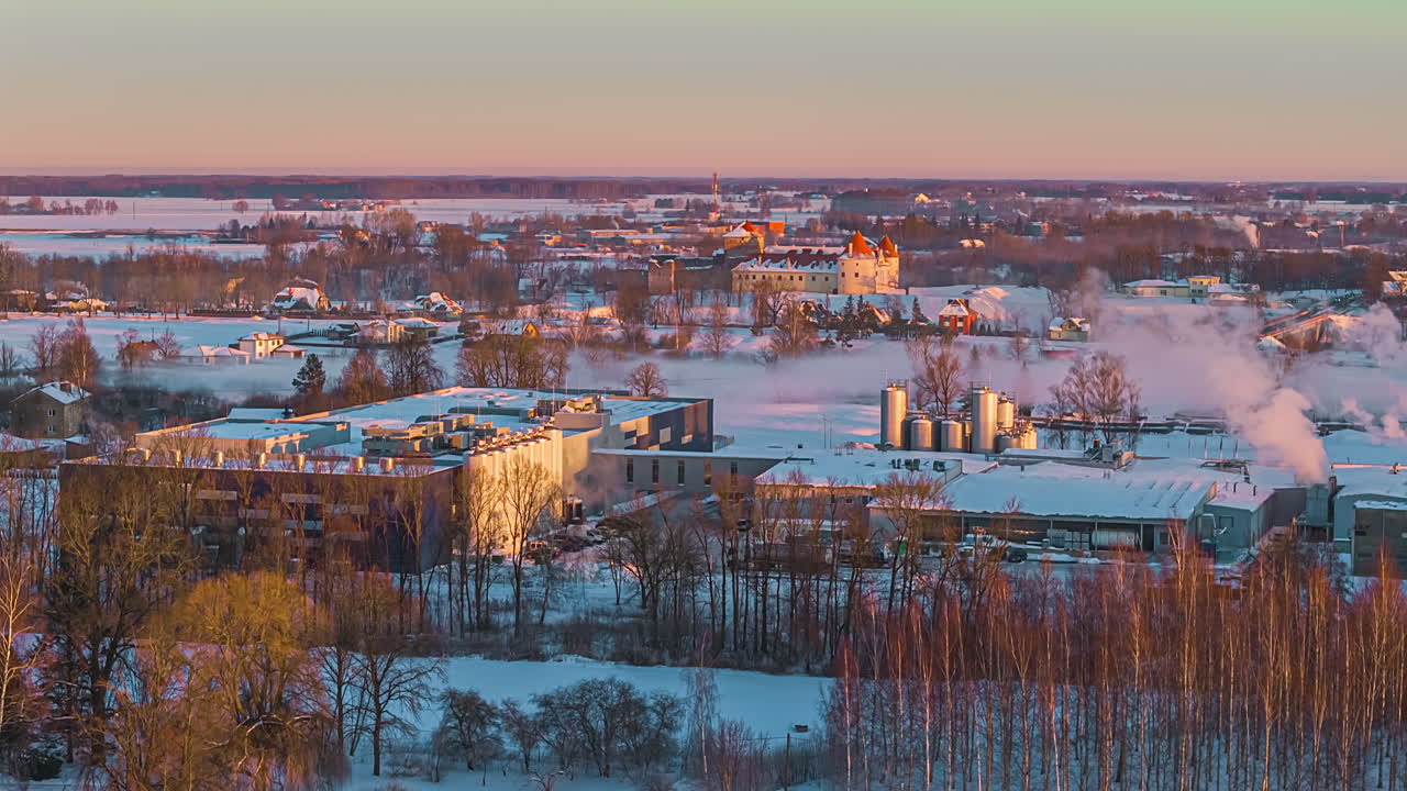 Talvinen teollisuusmaisema auringonlaskussa, taltioituna sulavana hyperlapsena.