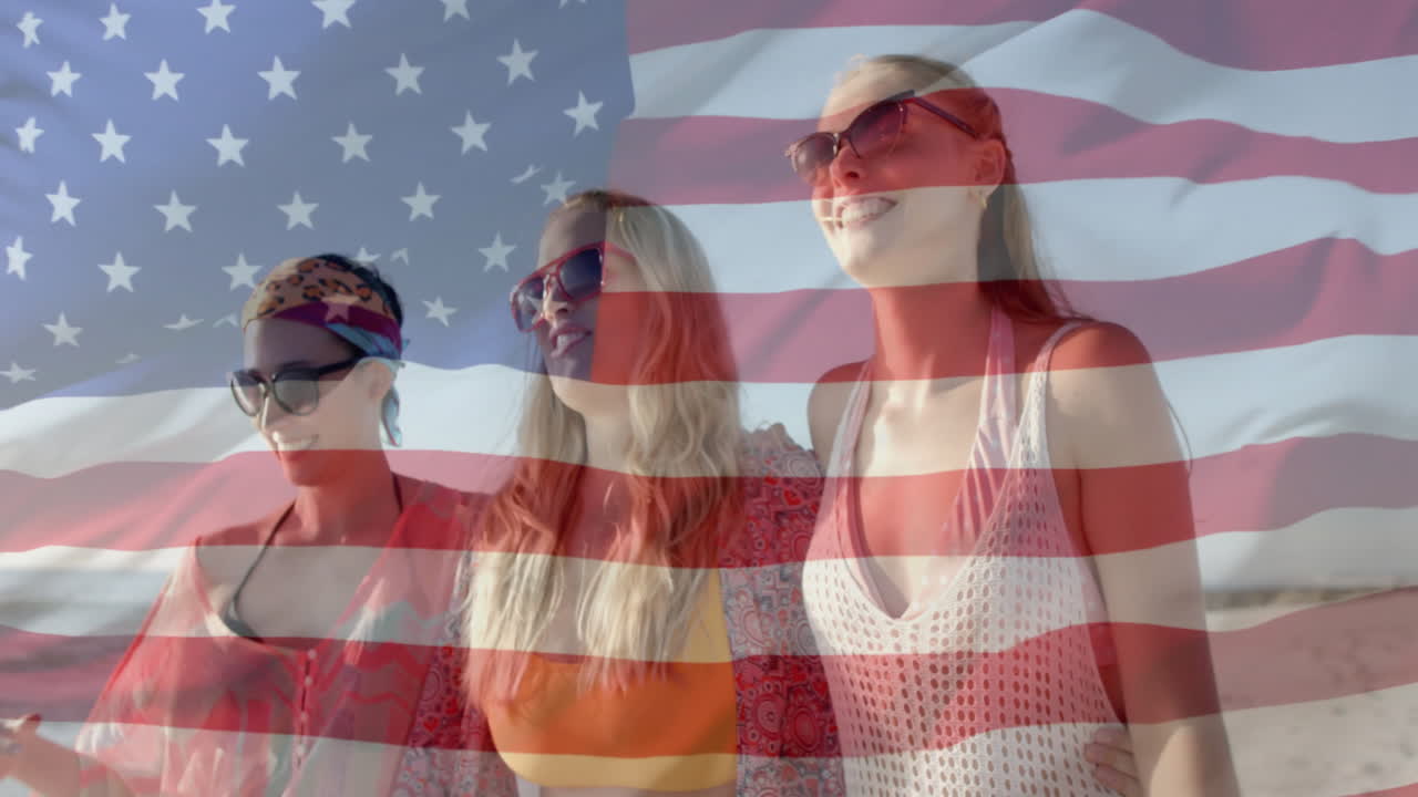 Animation of american flag over happy happy caucasian female friends walking on sunny beach