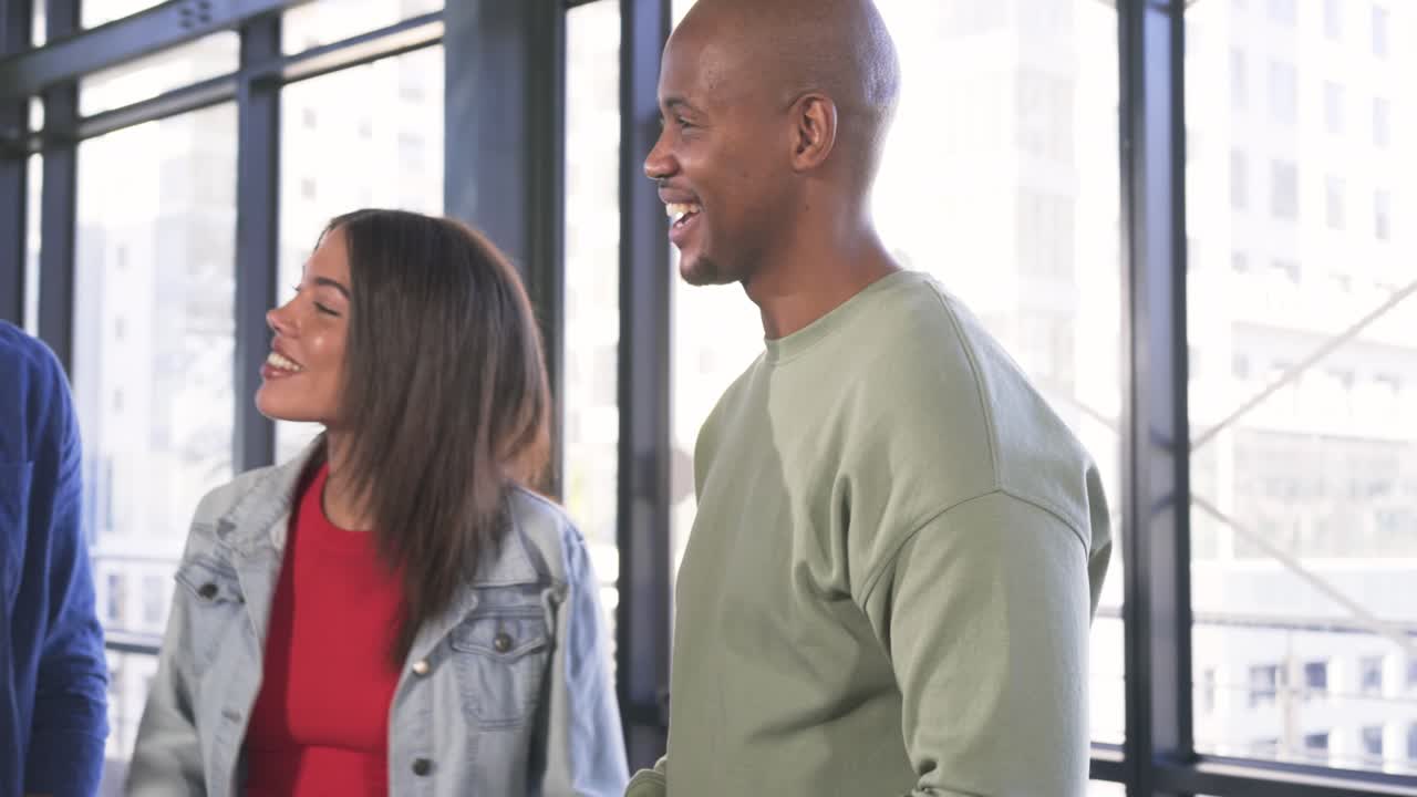 Diverse coworkers discussing with tablet at office, greeting new arrivals and smiling together