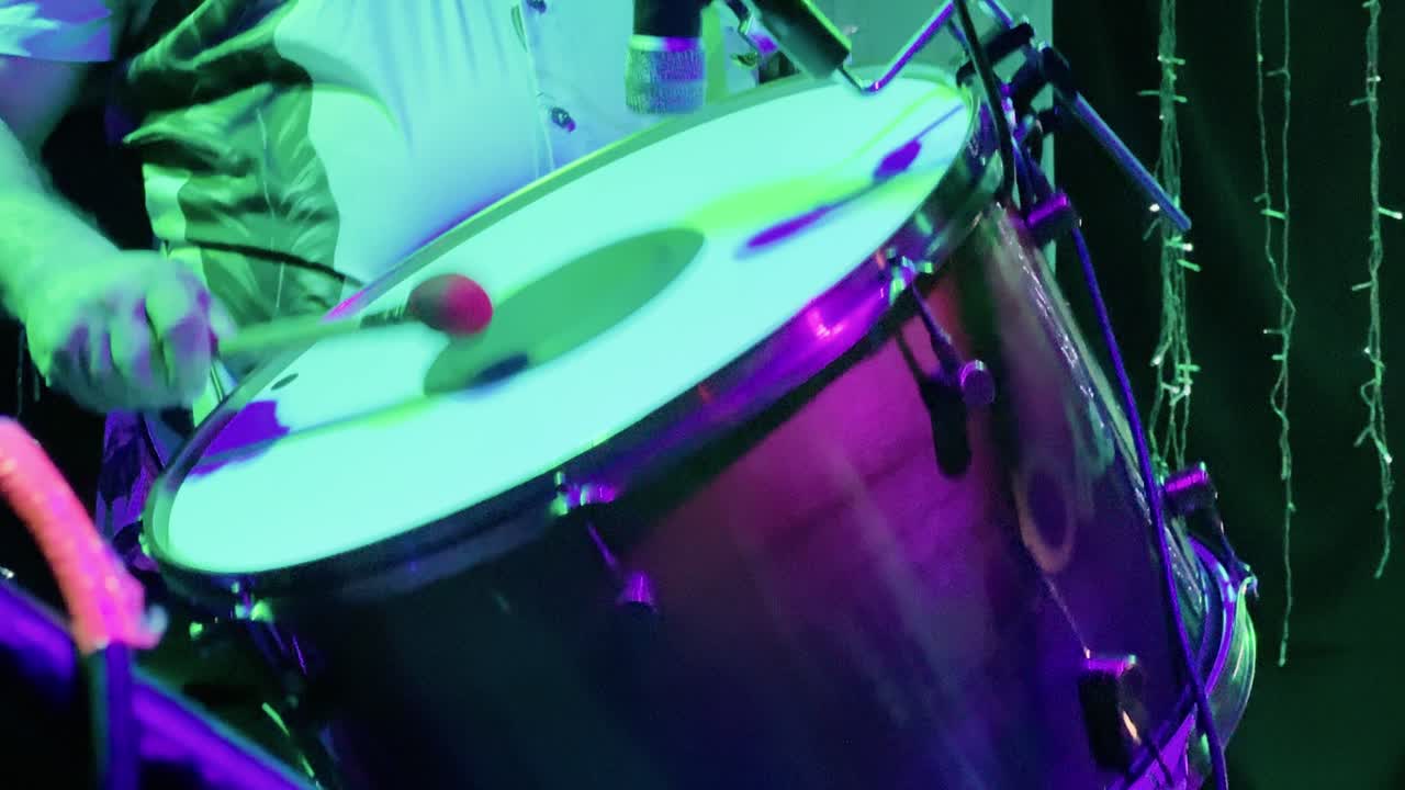 4K extreme close-up of a zabumba player striking the drum with precision during a forró performance. The warm glow of stage lights enhances the rhythmic energy of this traditional Brazilian party scen
