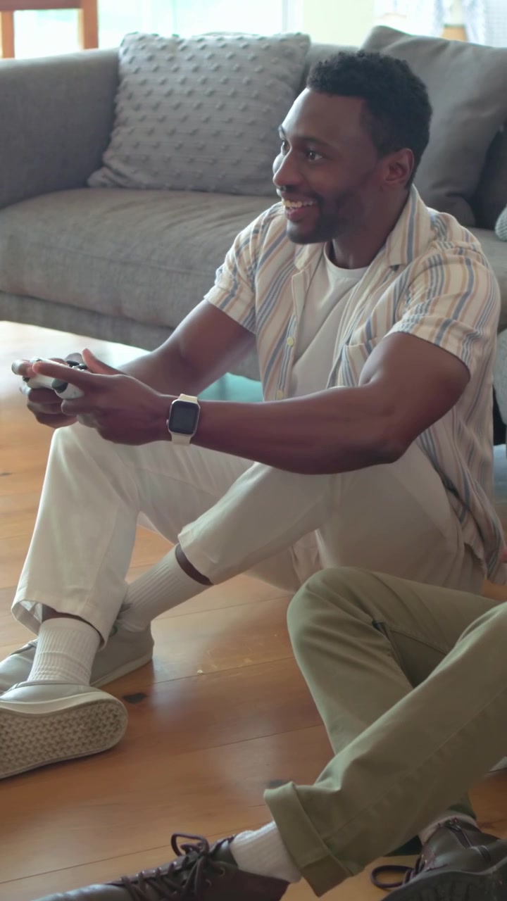 Vertical video: Leaning man in striped shirt holding pad as game starting, playing with pal at home