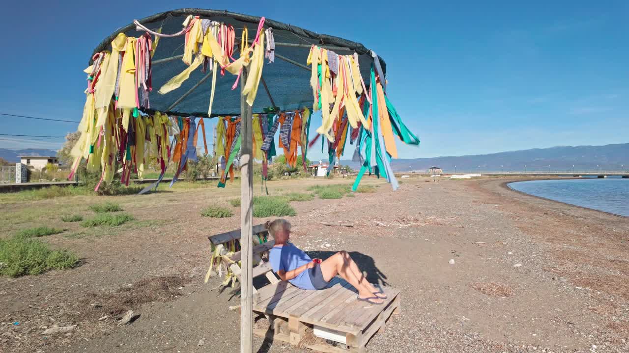 Woman relaxes on cheap budget holiday Greek deserted pebbled beach