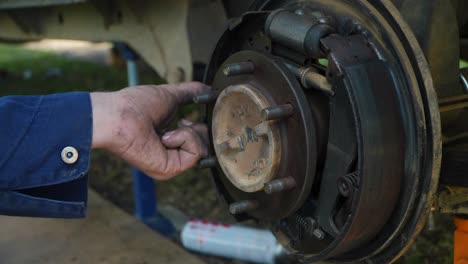 dirty hands of mechanic making adjustment to brakes of vehicle, close up