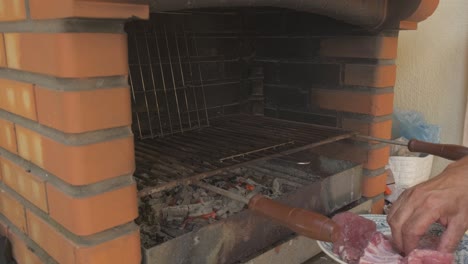 hombre asando carne en una parrilla tradicional con la cabeza descubierta y gran experiencia