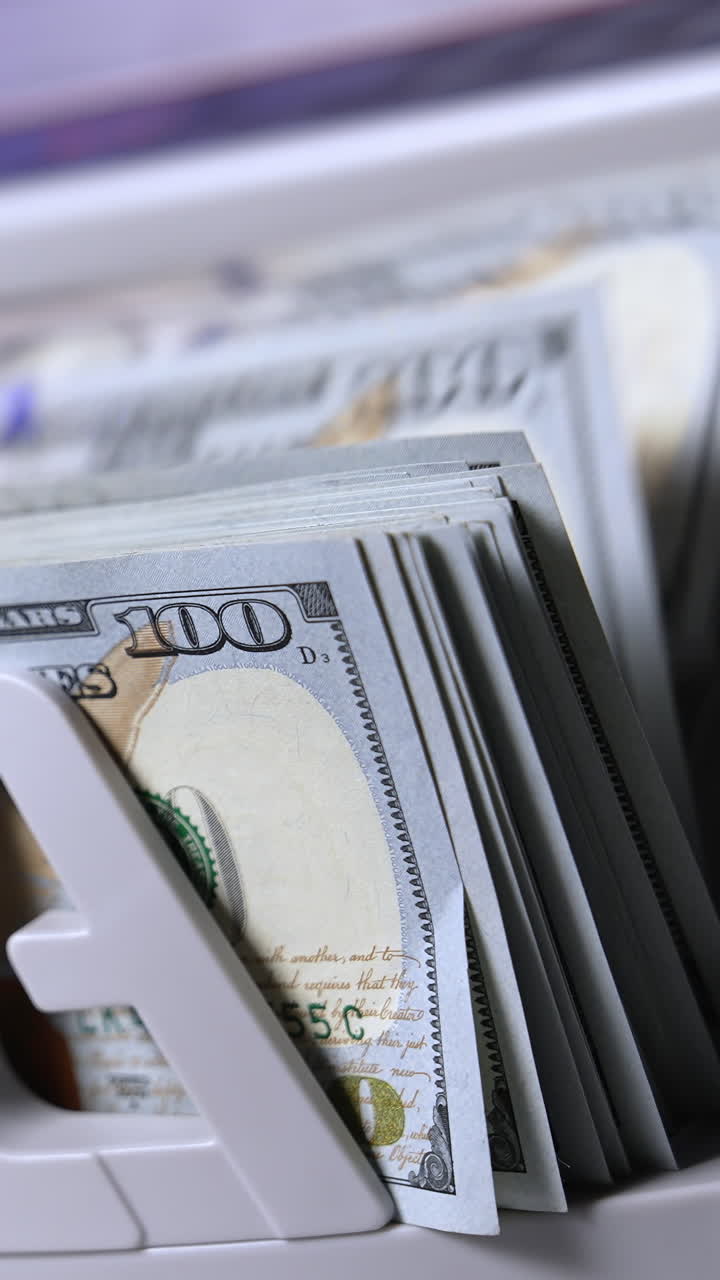 Counting hundred of dollar bills in bank. Financial operation on a modern electronic cash counting machine. Automatic equipment for counting paper money. Vertical video