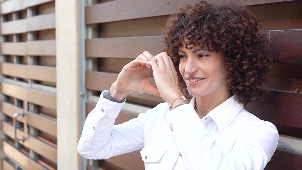An elegant woman with beautiful curly hair posing gracefully against a wooden background