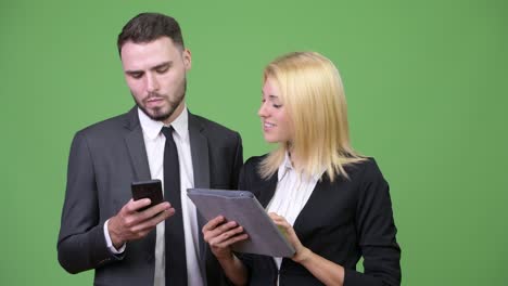 una joven pareja de negocios usando una tableta digital y un teléfono inteligente juntos