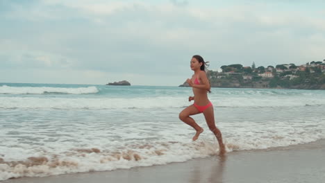 Sporty-woman-running-along-coastline-in-warm-day.-Athlete-girl-enjoying-sea-run