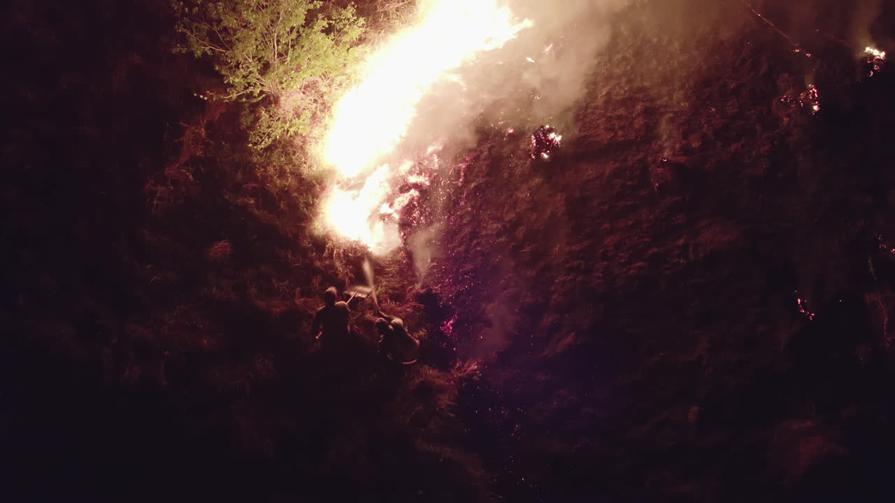 Fire fighter putting off the fire using shovels and flashlights. Criminal fire with great destruction.Aerial drone view show all the action.