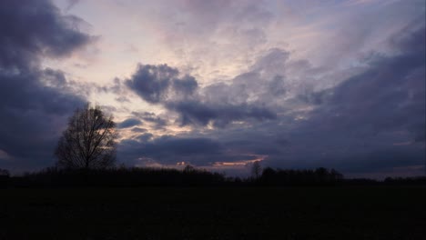 dramatic dark cloud timelapse during evening with tree silhouette, latvia