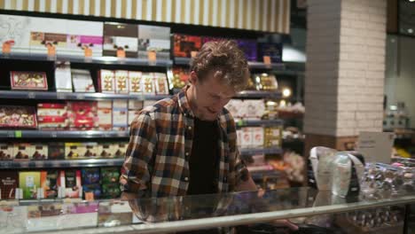 Portrait-of-handsome-man-in-plaid-shirt-walking-and-looking-around-in-supermarket.-Mature-guy-in-30s-searching-for-products-while-doing-shopping-in-grocery-store.-Staring-at-showcase