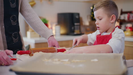 el niño ayuda a papá a hacer galletas de pan de jengibre de navidad.