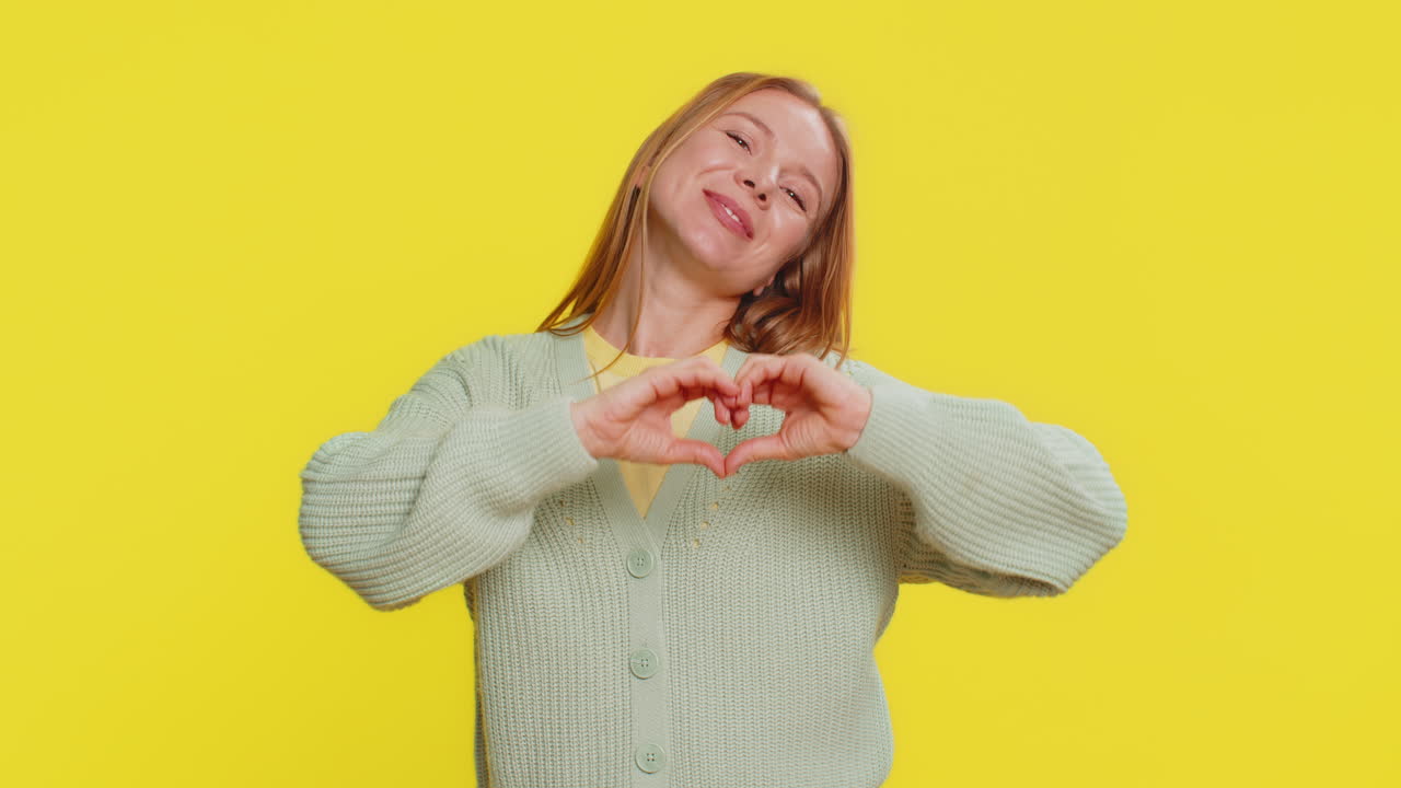joven sonriente hace un gesto de corazón demuestra un signo de amor expresa buenos sentimientos y simpatía