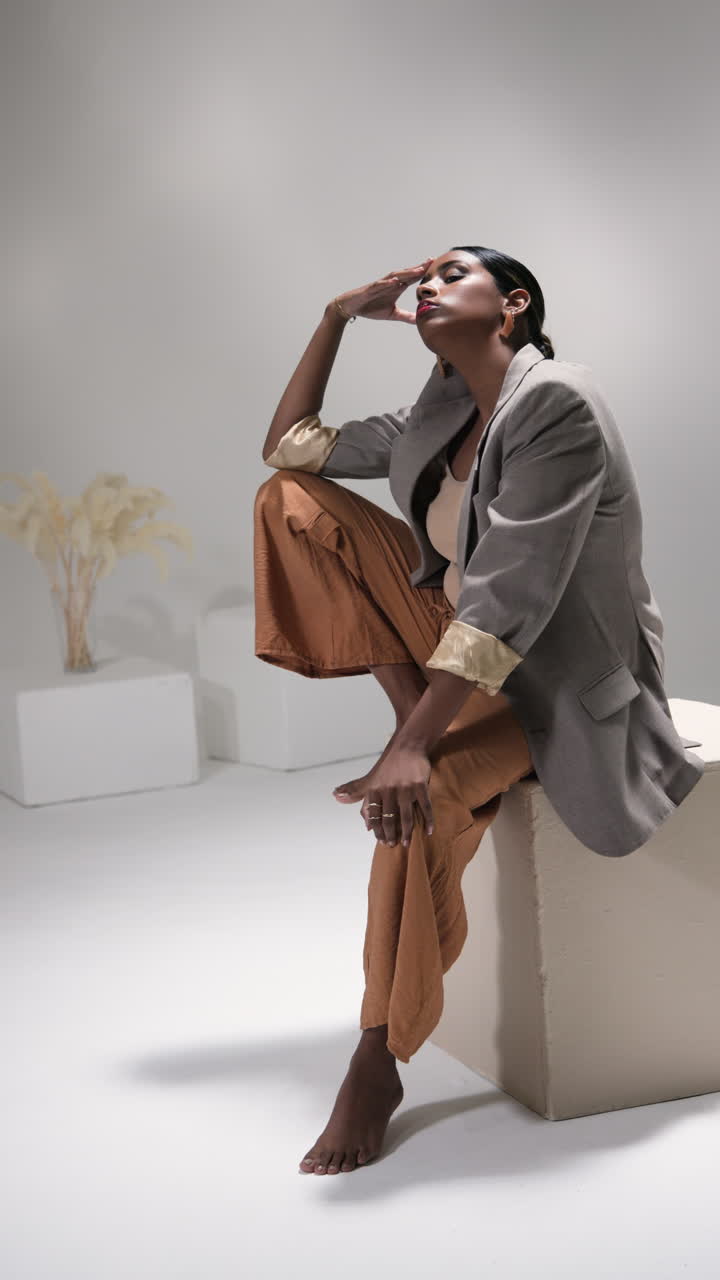 Vertical video: Confident woman in stylish outfit posing gracefully in modern fashion studio