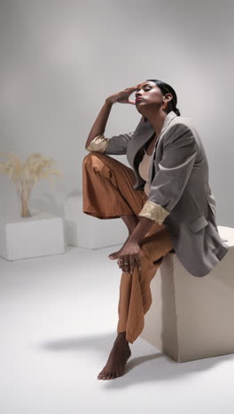 vertical video: confident woman in stylish outfit posing gracefully in modern fashion studio
