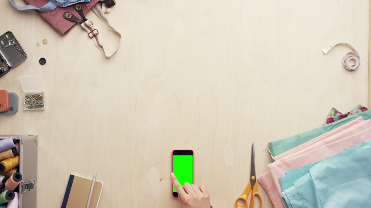 vista superior de las manos del diseñador de moda usando una aplicación de diseño de teléfono móvil trabajando en el escritorio desde arriba - dragón épico rojo