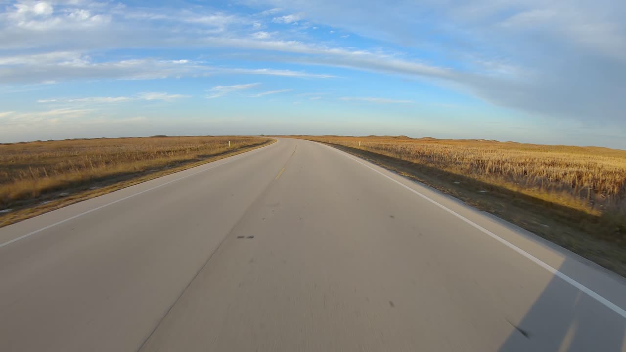 pov mientras conduce por una carretera pavimentada a través de las praderas pantanosas de la isla barrera del padre norte a lo largo de la costa del golfo de texas al final de la tarde