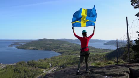 woman walks on a mountain in slow motion with a waving flag above her head