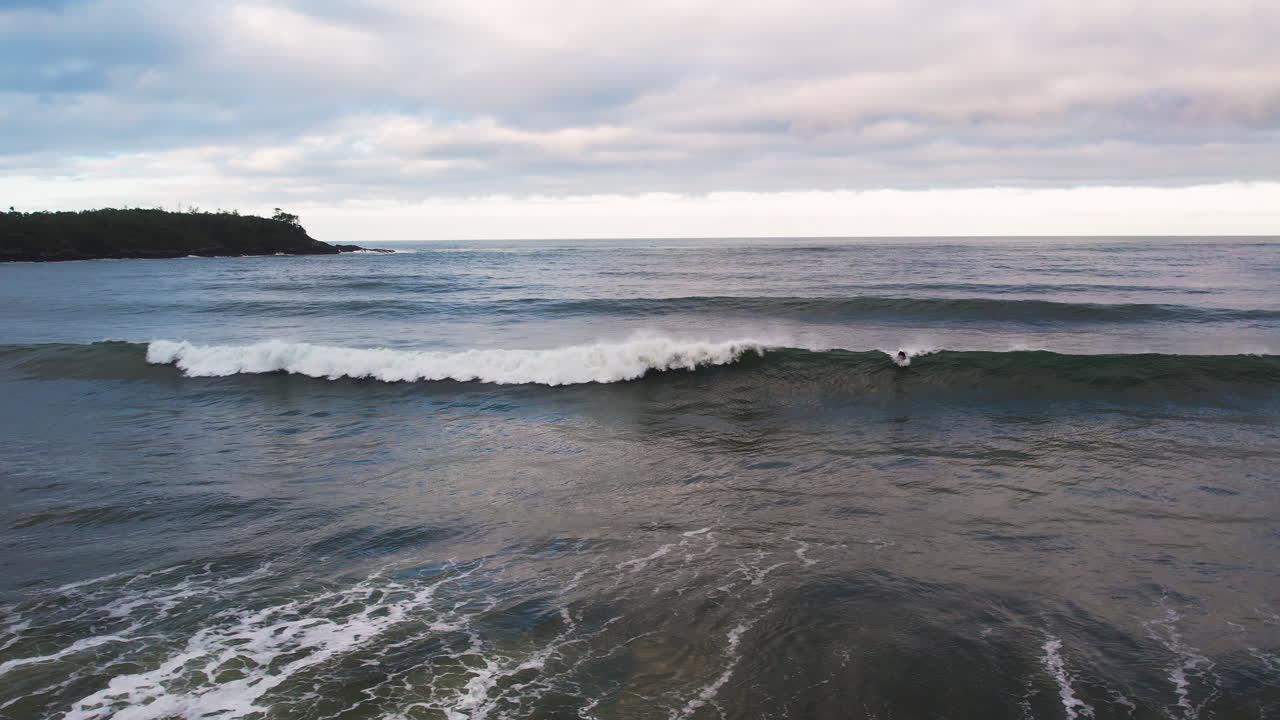 el surfista atrapa una buena ola en la playa de cox bay al atardecer, tofino, bc