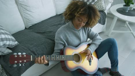 mujer relajada tocando la guitarra en casa