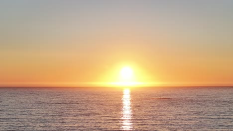 bright orange sun during sunset in the ocean