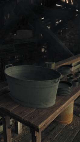 an old metal bucket sits on a rustic wooden table in a barn.