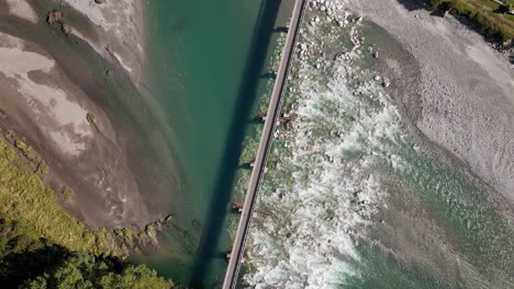 narrow bridge leading over shallow, green glacial river