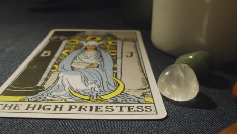 close up shot of person giving tarot card reading laying down the high priestess , strength and death cards on table