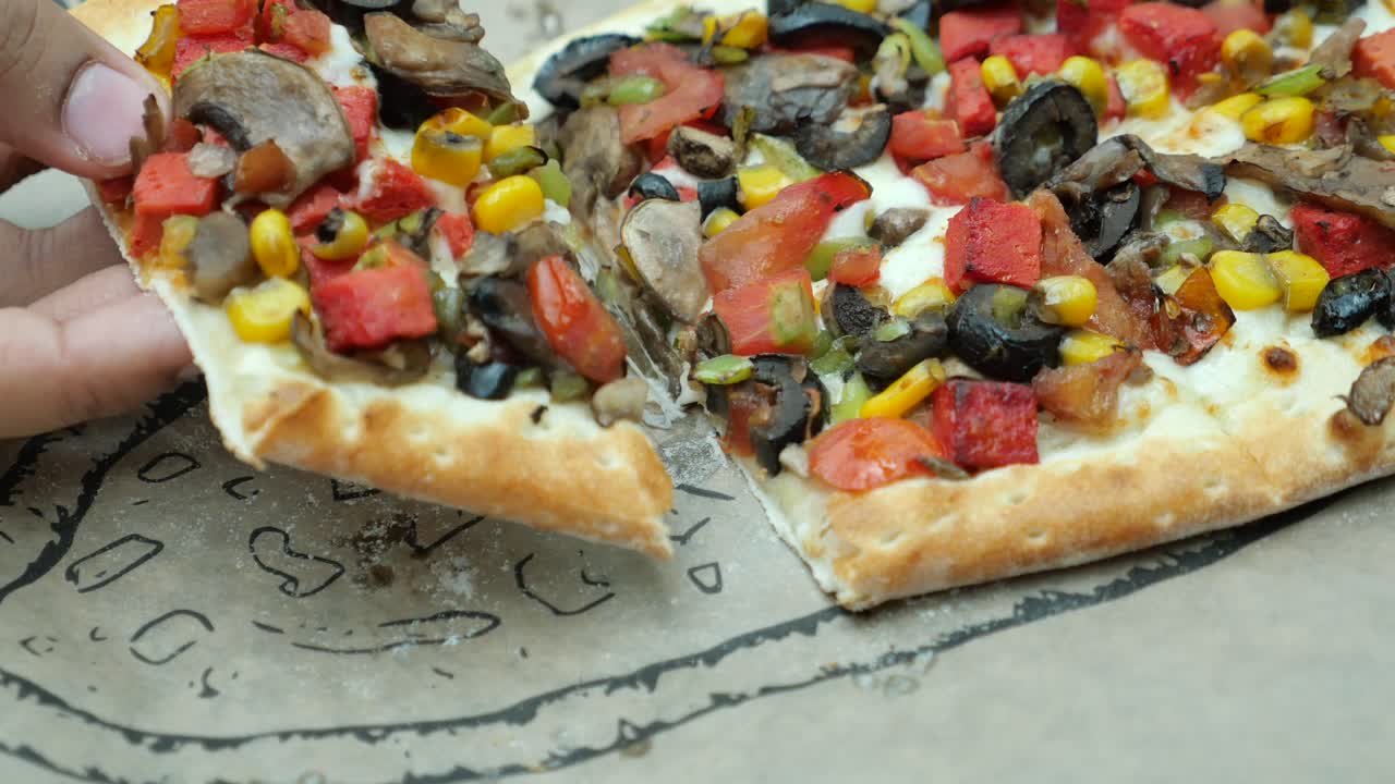 recogiendo a mano una rebanada de pizza turca