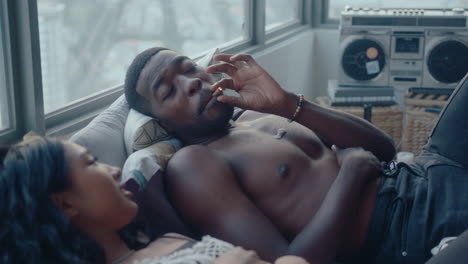 young happy couple chatting and smoking on bed