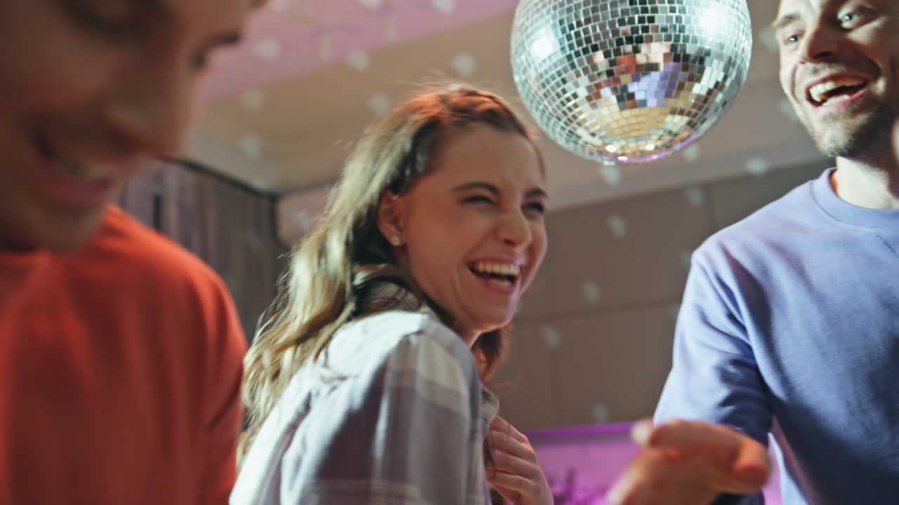 Laughing friends dancing home under disco ball closeup. Joyful people having fun