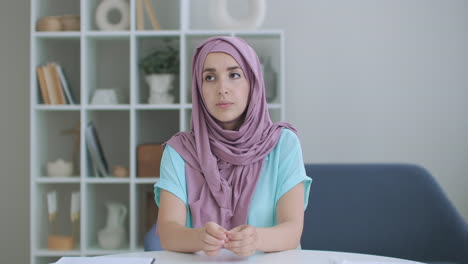 Una-Mujer-Con-Hijab-Mira-A-La-Cámara,-Asiente-En-Silencio-Con-La-Cabeza-Y-Escucha.-Conversación-A-Través-De-Un-Enlace-De-Vídeo.-Videoconferencia-Escucha-Las-Recomendaciones-Del-Médico.