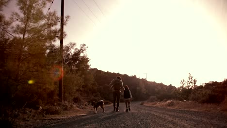 father and son hiking with pet dog in nature