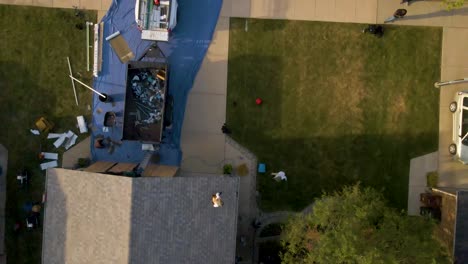 aerial view of construction workers laboring in a backyard patio with outdoor furniture, a fire pit, and a well-maintained lawn, showcasing a cozy and inviting outdoor living space.