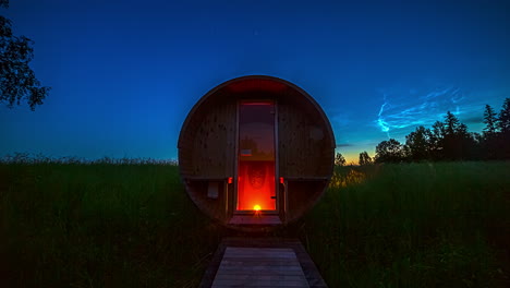 time lapse shot of empty barrel sauna in rural countryside during sunset and bright sunrise in the morning - night to day transition