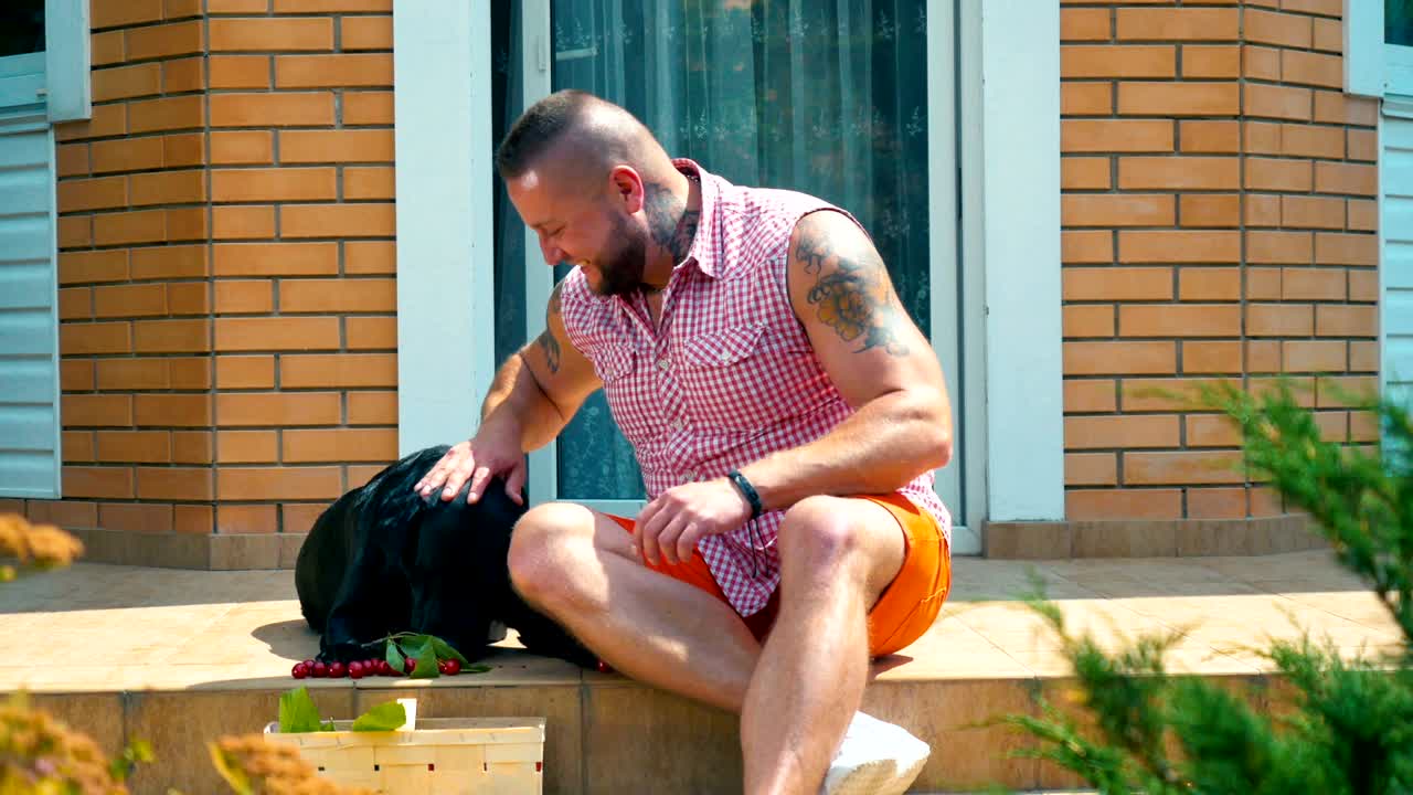 미소 짓는 남자 는 개 에게 체리 를 먹이고 야외 에서 함께 즐거운 시간 을 보낸다