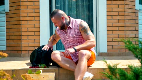 un tipo sonriente alimenta a su perro con cerezas y se divierten juntos al aire libre.