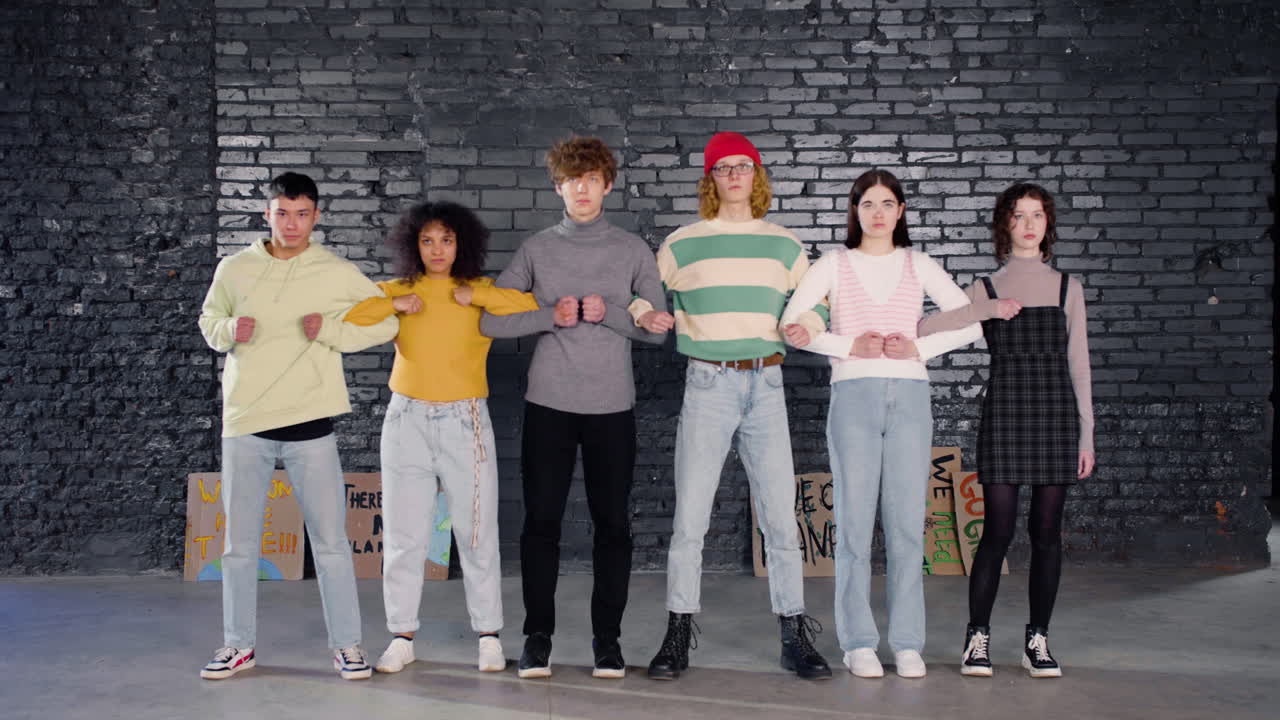 진지한 젊은 환경 운동가들이 팔짱을 끼고 기후 변화의 무활동에 항의하는 장벽을 형성하고 있습니다.