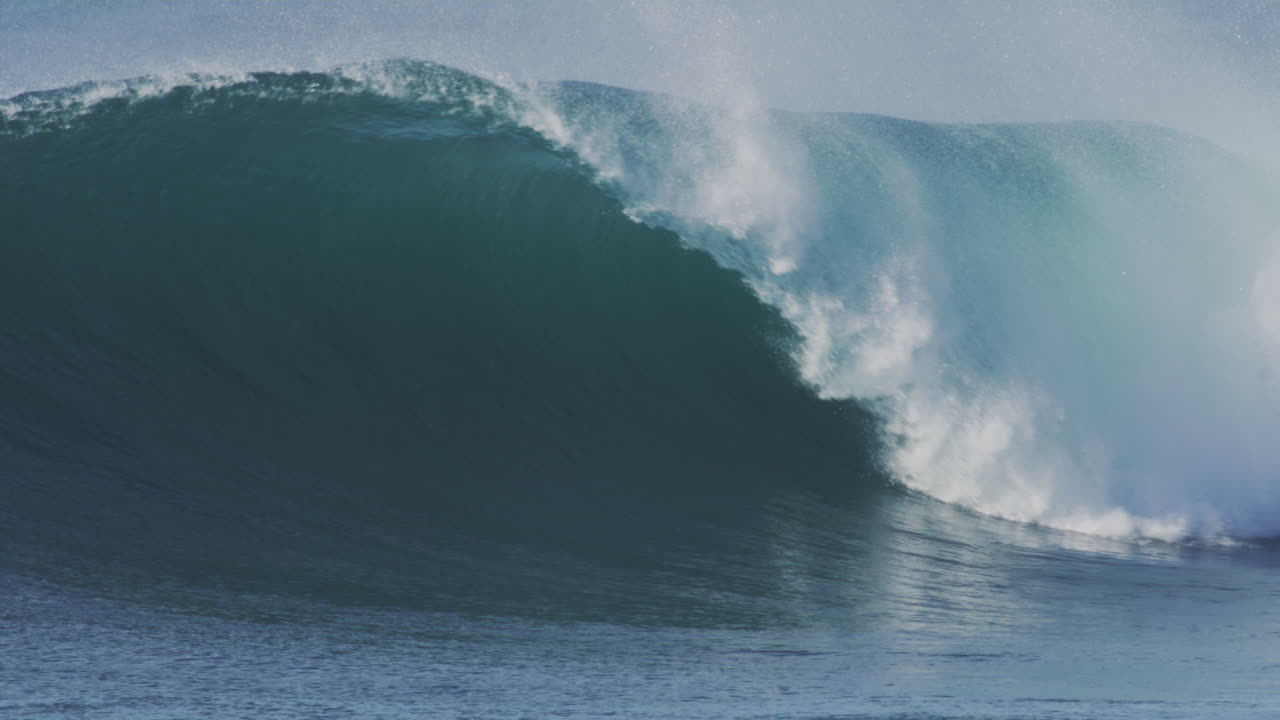 olas gigantes rodan en cámara lenta en la hora dorada, capturando la textura de la ola y el fondo tranquilo del océano