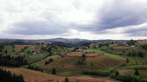 aerial picturesque agricultural green hill land with houses in countryside