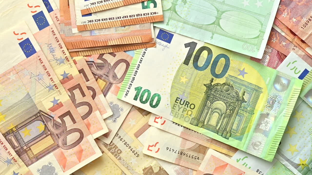 Primer plano de varios billetes de cincuenta y cien euros esparcidos sobre una superficie