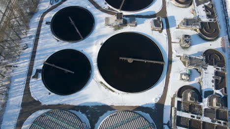 top down aerial of water basins and tilting up, revealing sewage treatment plant in winter