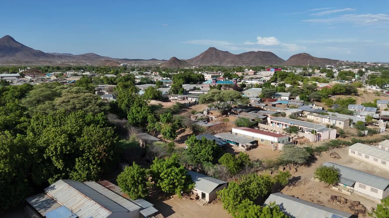 Veduta aerea di Lodwar, Contea di Turkana, Kenya, che mostra vegetazione verde, edifici bassi e colline rocciose nel paesaggio arido settentrionale.