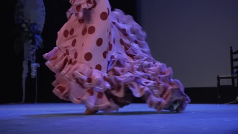 flamenco dancer heels hard and moves the tail of pink dress with red polka dots on stage