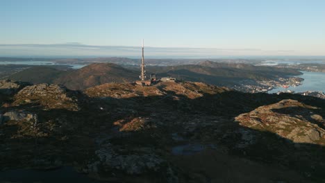 Tonos-Del-Atardecer-Sobre-Ulriken,-Bergen-Con-Una-Torre-De-Radio-Dominando-El-Paisaje,-Las-Sombras-Se-Extienden-A-Lo-Largo