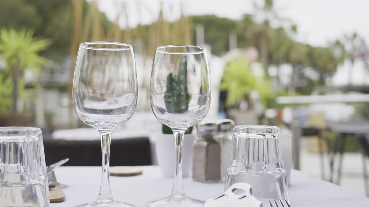 Close up of glasses on a set table at a terrace with people walking on the blurred background