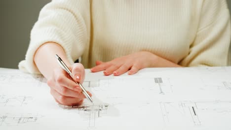 person drawing on blueprints