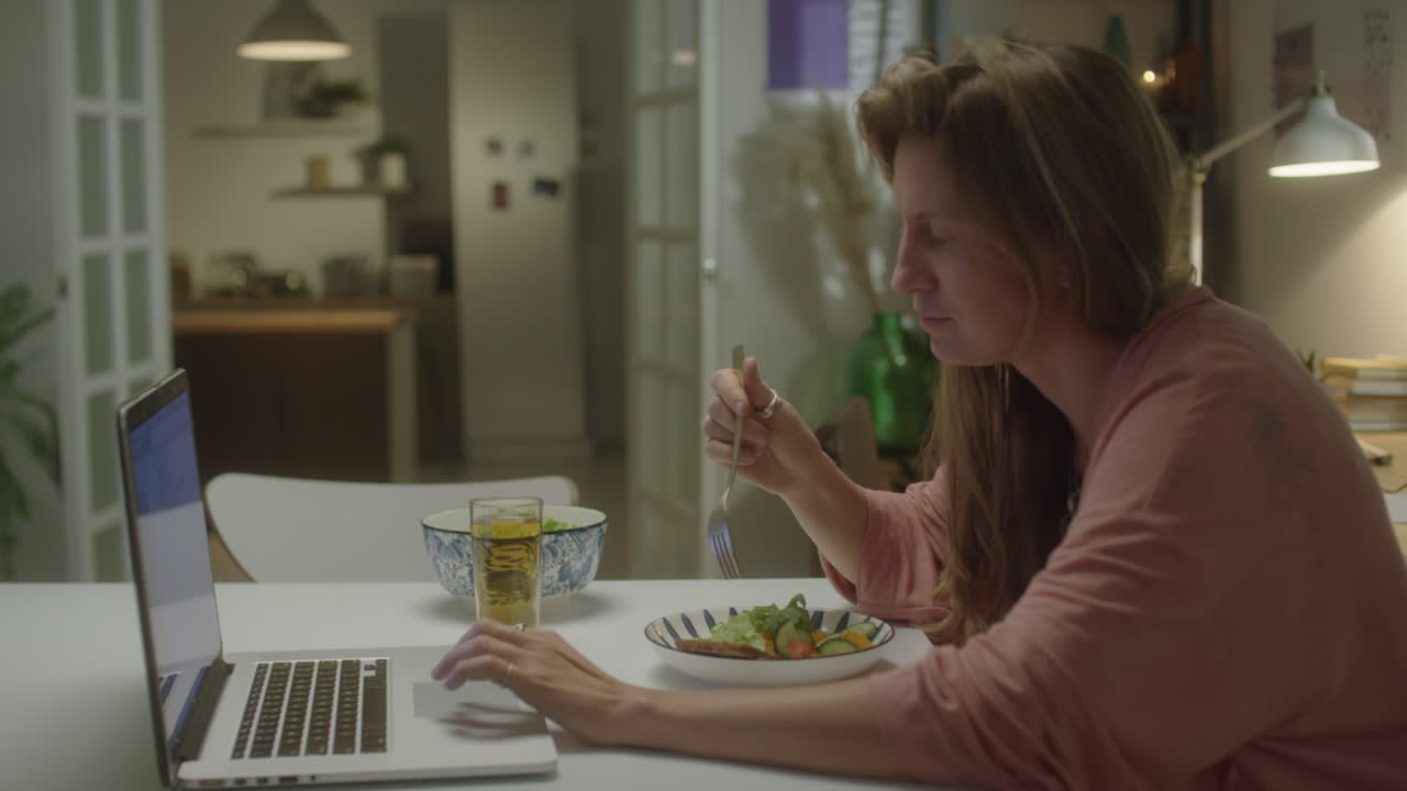 Woman Eating Dinner and Using Laptop